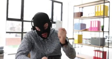 Maskeli ve kulaklıklı bir adam online hırsızlığın olası kurbanıyla görüntülü görüşme yapıyor. Sahtekarlık, hayali projeye yatırım yapmaya ikna etti.