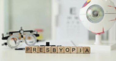 Kelime Presbyopia tahta küplerden yapılmış, gözlük ve insan gözü modeline karşı. Göz hekimliği kliniğinde kırılma hatası teşhisi