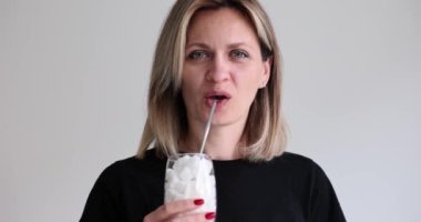 Bir bardak şekerden samanla içen güzel bir kadının portresi. Şeker küpleriyle dolu bardaklar