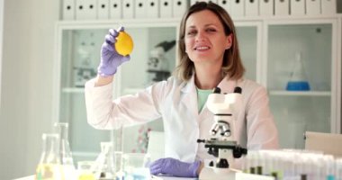 Mikroskop kullanan bilim adamları limonu laboratuvarda tutuyor. Limonların faydaları ve zararları ve C vitamininin yararlı özellikleri