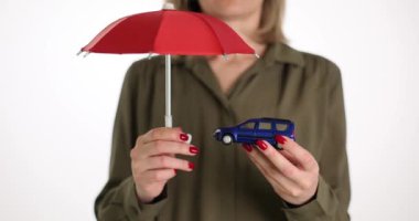 Kadın arabanın üzerinde şemsiye tutuyor. Araba koruma sembolü. Otomobil sigortası ve nakit ödemeler