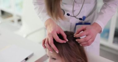 Çocukların saçlarını kontrol eden kadın trikoloğa yakın çekim. Bir çocuğun saçındaki parazitler ve pediküloz belirtileri.