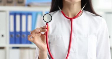 Klinikte kırmızı steteskop tutan kadın doktor. 4K 'lık filmi yavaş çekimde. Profesyonel tıbbi danışmanlık kavramı