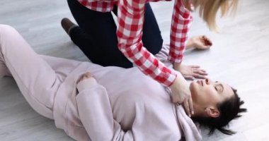 Karotis arterin nabzına bakan bir kadın ve bilinçsiz adam 4K filmine dolaylı kalp masajı yapan bir kadın. Kardiyopulmoner canlandırma kavramı
