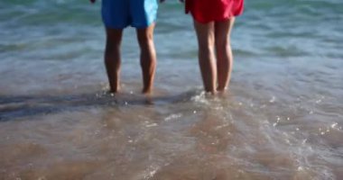 Mutlu adam ve kadın güneşli bir günde deniz dalgalarıyla yıkanan sahilde yükseğe zıplarlar. Birbirine aşık çiftler yaz tatilinin tadını yavaş çekimde çıkarır.