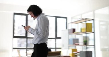 Sinirli adam yönetici şirket ofisinde cep telefonundan mesaj atıyor. Genç çalışanlar odada akıllı telefondan iletişim kuruyor.