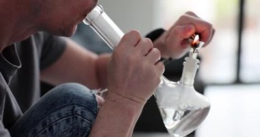 Adam ışık odasında psikoaktif maddeyle nargile içiyor. Bağımlı kişi uyuşturucu almak için cihaz kullanır. Tehlikeli bağımlılık belirtileri