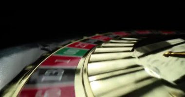 Renkli hücreli çark ve numaralar koyu arkaplanda döner ve durur. Kumarbazlar rulet oynarlar Modern kumarhanede şans denerler