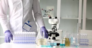 Laboratuvar kadın çalışanı, masada cam eşyalar ile tıbbi araştırmalar için mikroskop hazırlıyor. Ağır çekimde gülümseyen kadın bilim adamı.