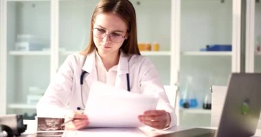 Profesyonel doktor klinikteki hastanın test sonuçlarını inceliyor. Kadın sonuçları ağır çekimde dizüstü bilgisayarla kontrol ediyor.