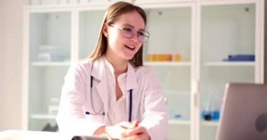 Profesyonel doktor bilgisayardaki görüntülü konuşma yoluyla hastayla konuşuyor. Kadın uzmanlar teşhisi ve tedaviyi yavaş çekimde anlatır.