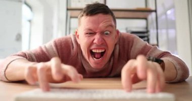 İnternette dolandırıcılık yapan heyecanlı adam ağır çekimde PC klavyesinde. Deli adam internette provokasyon hazırlıyor. Duygusal oyuncular odada oynar