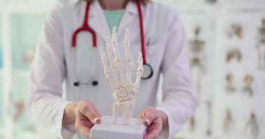 Steteskoplu kadın doktor el iskeleti tutuyor. Profesyonel tıp alanında kol iskeleti öğrencilere daha yavaş çekimde sunuluyor.