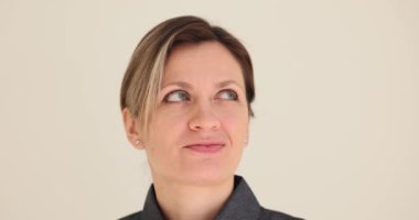 İlgili sarışın genç bayan etrafa bir göz atar. Mavi gözlü kadın gülümsüyor ve çevreyi beyaz duvara karşı ağır çekimde inceliyor.