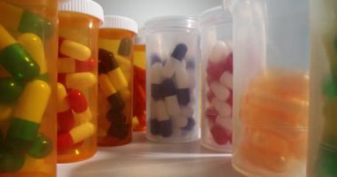 Turuncu ve şeffaf kapsüllü şişeler her iki tarafta da sıralanır. Sağlıklı vücut ve güzellik için çeşitli beslenme malzemeleri ve vitaminler.