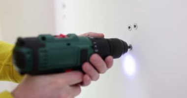 İşçi, yenilenmiş odada elektrikli tornavidayla vidaları söküyor. Becerikli inşaatçı ev sahiplerinin yavaş çekimde tamirat yapıyor.