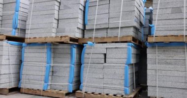 Depodaki paletlerin üzerindeki granit levhalar. Duvarları ve zemini tamamlamak için inşaat malzemeleri. Binaların iç ve dış tasarımı için dayanıklı malzeme