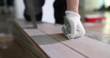 Uzman, parke tahtasını testereyle kesiyor. Koruyucu pamuk eldivenli profesyonel bir işçinin eli, malzemeyi keskin aletlerle yavaş çekimde yeniden boyutlandırır.