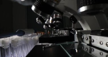 Modern mikroskoplar ve mantarlı cam test tüpleri. Laboratuvar ekipmanları karanlık odada. Bilimsel araştırma ve deneyler için yenilikçi araçlar