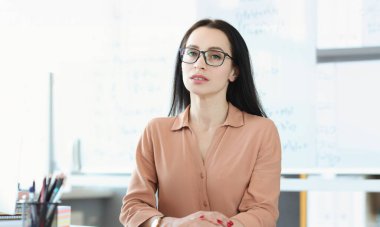 Çalışma masasında gözlüklü genç bir iş kadınının portresi. İş danışmanlığı ve personel eğitim kavramı