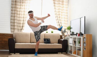 Spor giyim ve dambılı şişman adam fiziksel egzersiz yapıyor. Aşırı kilolu insanlar için motivasyon ve ev uygunluğu