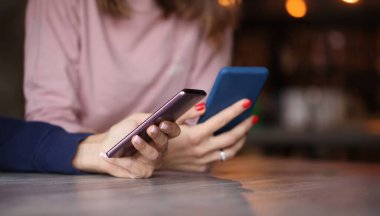 Kadın ellerinde iki akıllı telefon. Sohbet kavramı