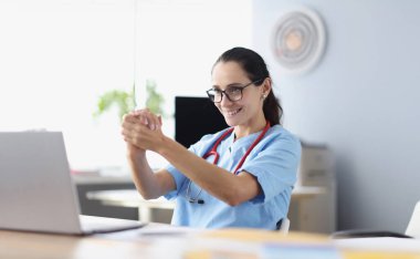 Gülümseyen kadın doktor dizüstü bilgisayar monitörüne bakar ve hastaya tavsiyelerde bulunur. Uzak tetemedicine konsepti