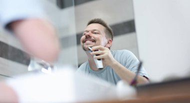 İnsan sakalını aynanın önünde makineyle tıraş eder sakal ve bıyık traşı kuralı konsepti