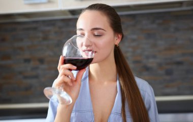 Güzel gülümseyen esmer kadın kolları bardak kırmızı şarap, mutfak masa portre tutun. Asma cabernet merlot sauvignon dudaklar güzellik kavramı