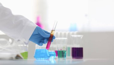 Bir erkek kimyager tüp elinde cam taşmaları potasyum permanganat yürüten bir analiz tepki alır çeşitli sıvı bir çözüm tutan kimyasal üretim kullanarak reaktifler sürümleri.