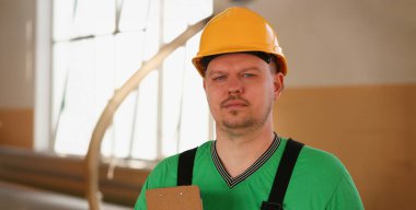 İş elbiseleri ve sarı kask geçti genç çekici adam portresi dükkanında mobilya üretimi için gülümseyen silah ve ev iç detaylar