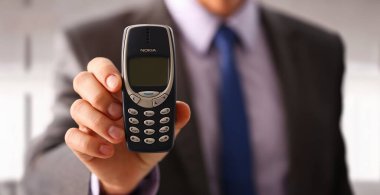 İllüstrasyon Editör İmajı. Minsk, Belarus, 1 Aralık 2024. İş adamı elinde klasik telefon Nokia 3310 'u tutuyor.