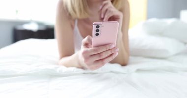 Akıllı telefonlu kesilmiş bir kadın yatağa uzanıp online video izliyor. Teknoloji boş zaman ve iletişim kavramı.