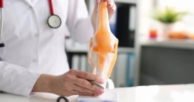 Doktor, dizdeki ağrıyı açıklıyor. Diz bağı anatomisi ve kemik athrosis konsepti