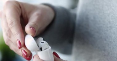 Kadın eli beyaz kablosuz kulaklıklı bir kutuyu açıyor. Moda tarzı kulaklık konsepti