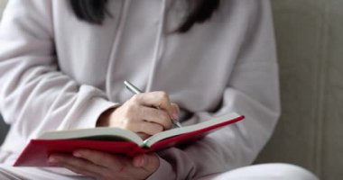 Kadın elleri evdeki kanepede günlüğe notlar yazar. Gazeteci mesleği veya günlük konseptine kişisel girdiler