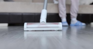 Hizmetçi, kablosuz elektrik süpürgesiyle yerleri temizliyor. Temizlik hizmetleri kavramı