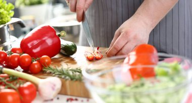 Close-up of male chef cutting hot pepper with sharp knife, veggies on cutting board, enjoy cooking. Person cook as hobby. Cooking, dish, homemade concept