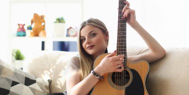 Portrait of young pretty woman playing on guitar, talented artist spend free time learning new song on musical instrument. Music, hobby, compose concept