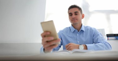 Portrait of concentrated worker using smartphone, chatting or surfing on internet. Kill time at work, bored, addiction, technology, digital world concept clipart