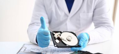 Üniformalı bir adam bilgisayardan, bilgisayardan ve okuyucudan sökülmüş sabit diski tutar. Bilgisayar cihazının tamir edilmiş parçası. Teknoloji konsepti