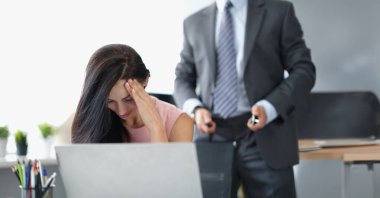 Patronunun tacizi yüzünden utanmış ve utanmış bir sekreter portresi. Pantolonunda fermuarı açık bir adam arkada duruyor. İş yerinde taciz