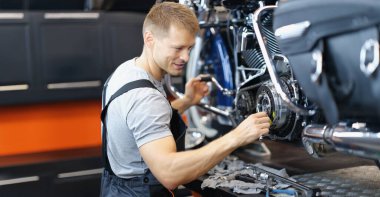 Garajda hasarlı motosikleti tamir eden yetenekli bir işçinin portresi. Üniformalı, tamirci, tamirci. Pit stop, servis yardım kavramı