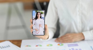 Kadın ofis çalışanının yakın çekimi ekranda doktor kadınla akıllı telefon göstermesi, niteliklerini değiştirmesi. Meslek değiştirecek kadar cesur. Geri çekilen konsept