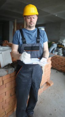 Meşgul profesyonel işçilerin portresi. Dosya ve çalışma materyalleri gerekli. Tamirci üniforma giyer ve koruyucu kask takar. İnşaat alanı kavramı