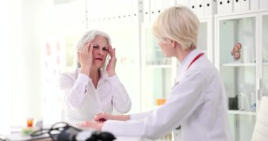 Olgun kadın masajları baş ağrısından şikayetçi ve ağrıyla başa çıkamıyor. Dikkatli doktor hastayı kontrol ediyor. Yavaş çekimde notlar alıyor.