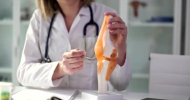 Deneyimli bir doktor, insan kemikleri ve eklemlerinin gerçekçi bir modelde olduğunu gösteriyor. Üniformalı kadın detaylı vücut kısmı ağır çekim gösteriyor.