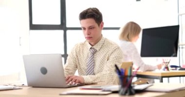 Konsantre adam internet sitesindeki istatistikleri dizüstü bilgisayarla kontrol ediyor. Ciddi yönetici, ofiste bilgisayarla çalışan meslektaşlarına karşı masada oturuyor.