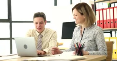 Meraklı meslektaşlar verileri karşılaştıran dizüstü bilgisayarlara ve araştırma belgelerine bakarlar. Heyecanlı erkek ve kadın takım projesinde birlikte oturuyorlar.