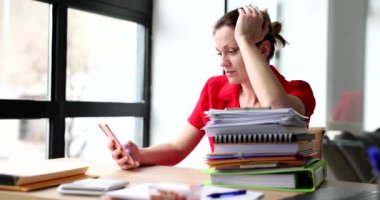 Yorgun kadın sosyal medyayı kontrol ediyor evrak işlerine ara veriyor. Yoğunlaştırılmış sekreter, iş yerinde ağır çekimde akıllı telefon kullanır.